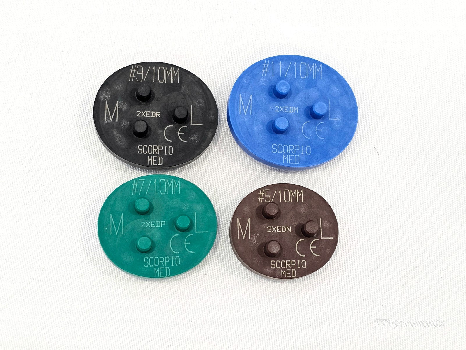 Four Stryker Scorpio MED dome patella drill templates: black #9/10mm (2XEDR), blue #11/10mm (2XEDM), green #7/10mm (2XEDP), brown #5/10mm (2XEDN), showing M/L orientation markings and CE marks