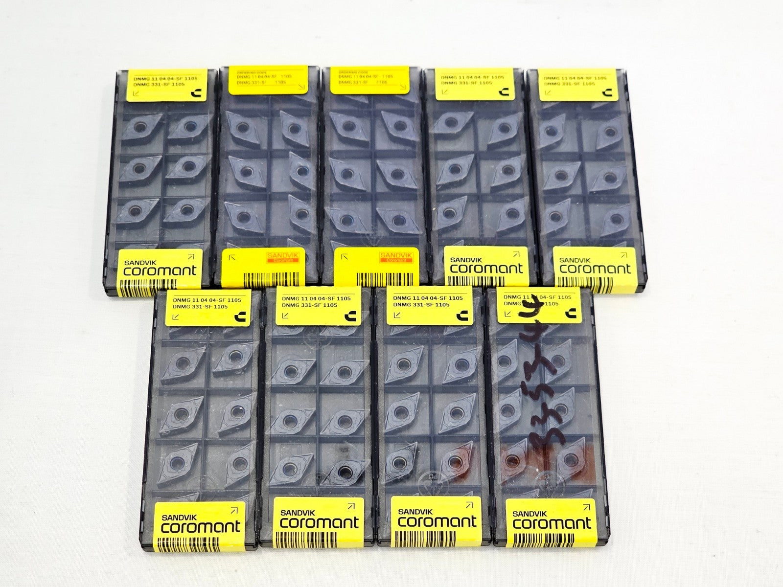 Nine Sandvik Coromant DNMG 110404-SF 1105 carbide insert blister packs arranged in two rows on white surface