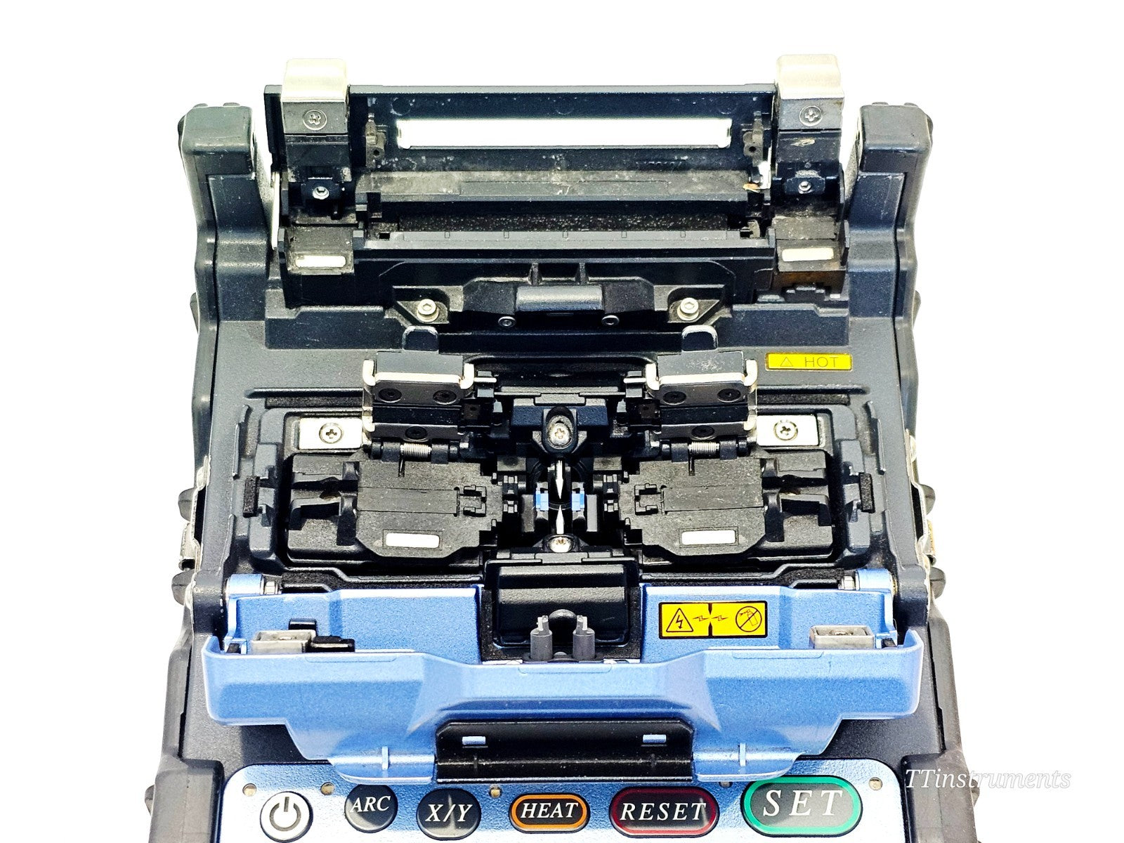 Fujikura FSM-62S+ splicer top-down view with wind protector open, showing V-grooves, fibre clamps and HOT warning label