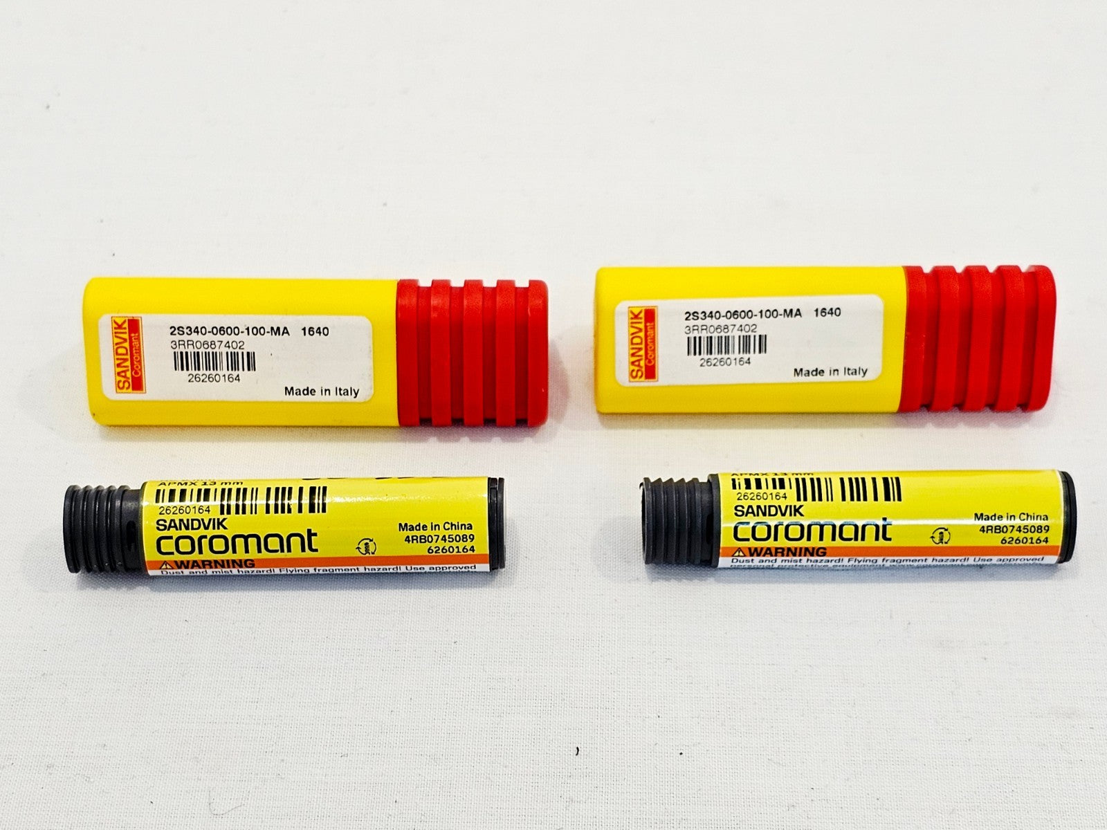 Sandvik Coromant 2S340-0600-100-MA 1640 CoroMill Plura end mills — two cutters with yellow/red tubes and grey plastic canisters