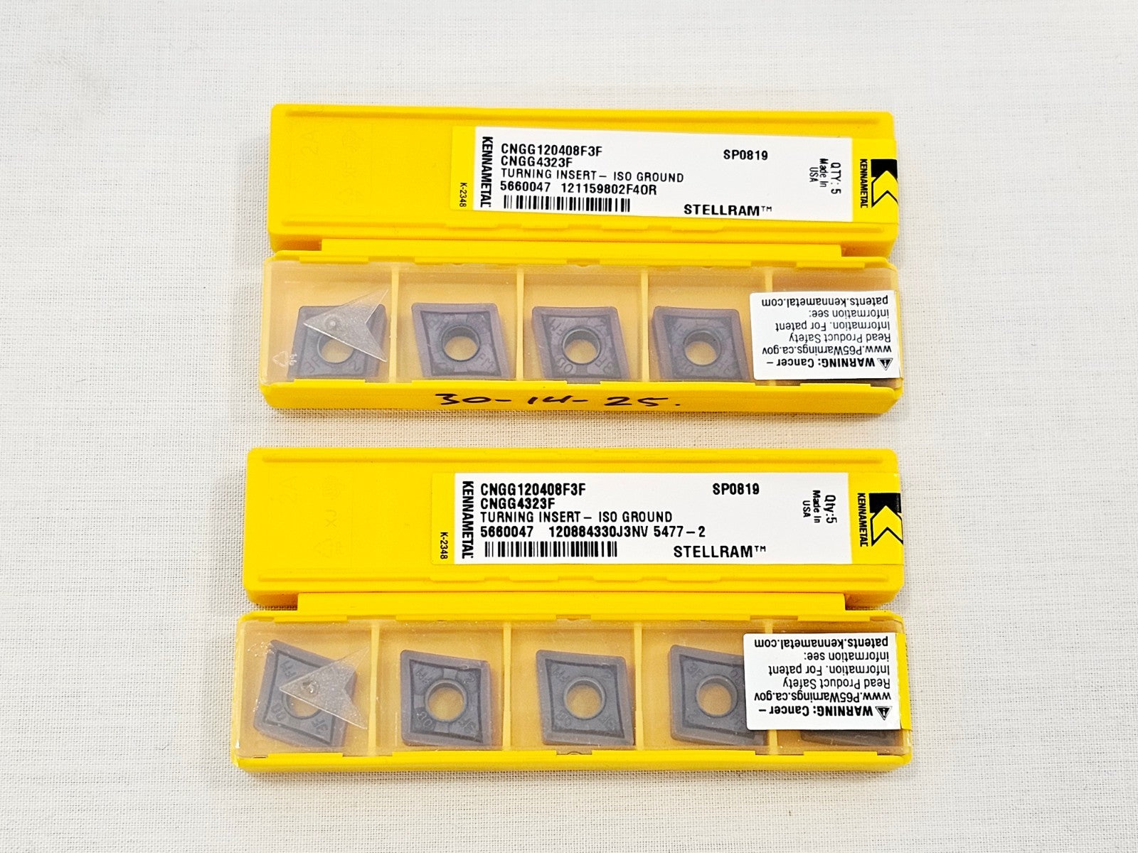 Two open Kennametal CNGG120408F3F SP0819 Stellram insert packs showing 5 carbide inserts each in yellow plastic trays