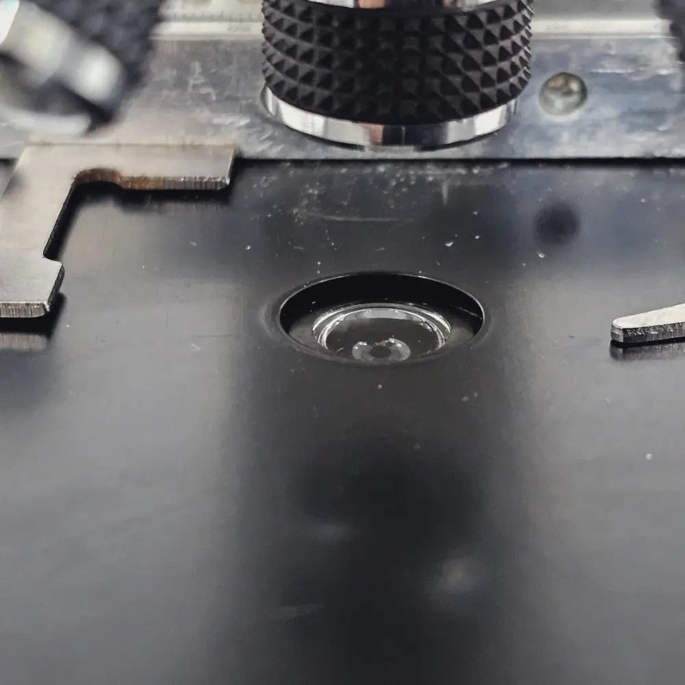 Top-down view of compound microscope stage showing slide clips and specimen platform