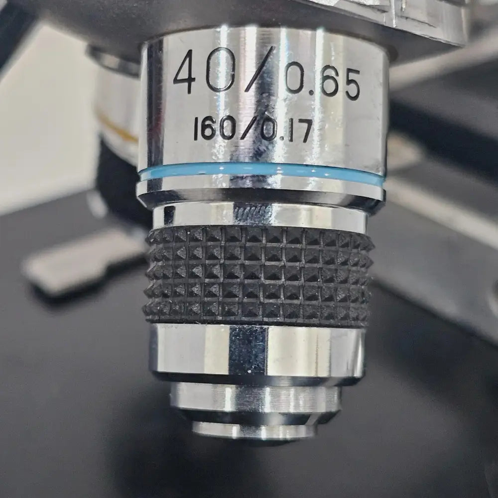 Compound microscope with 4/0.1, 10/0.25 and 40/0.65 objectives shown powered up with illumination active