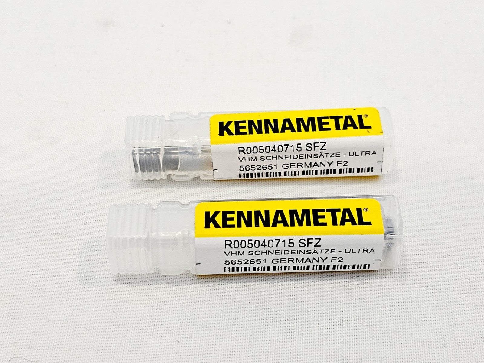 Two Kennametal R005040715 SFZ carbide threading inserts in original protective vials, top-down view