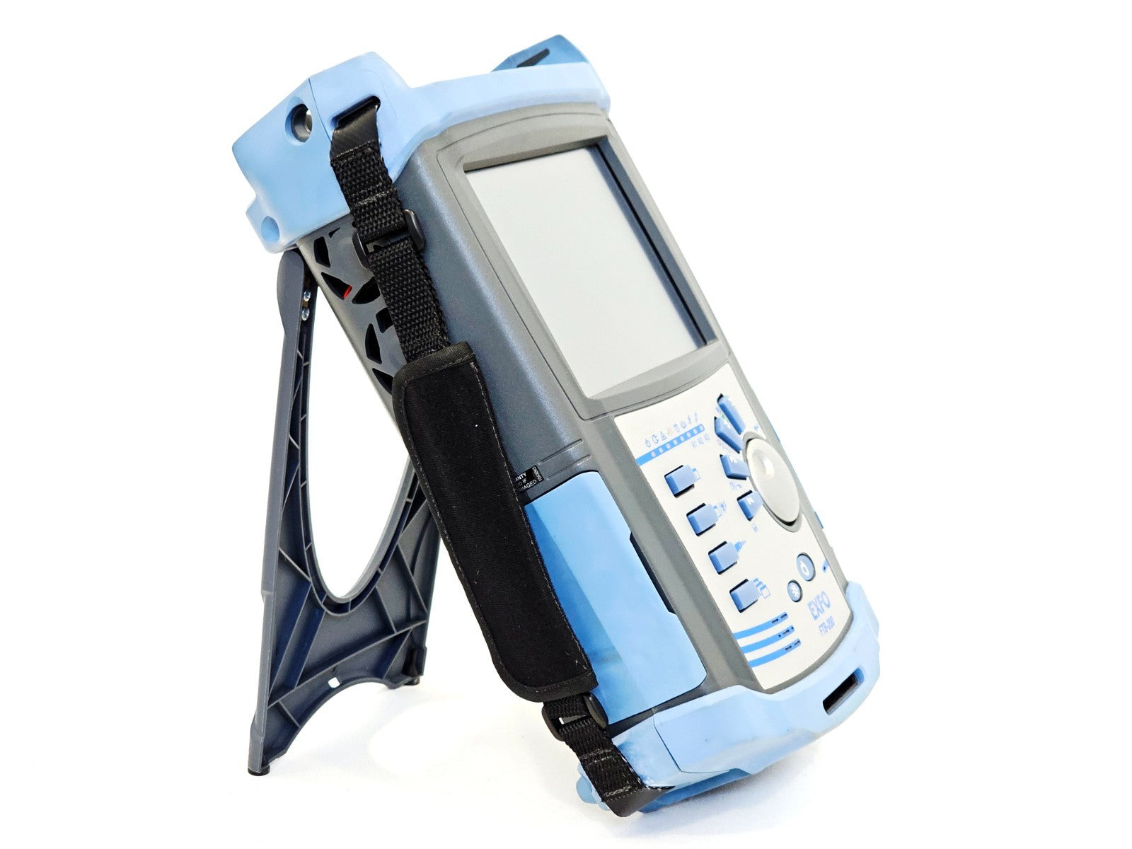 EXFO FTB-200 rear three-quarter view on stand showing hand strap and warranty void label on battery