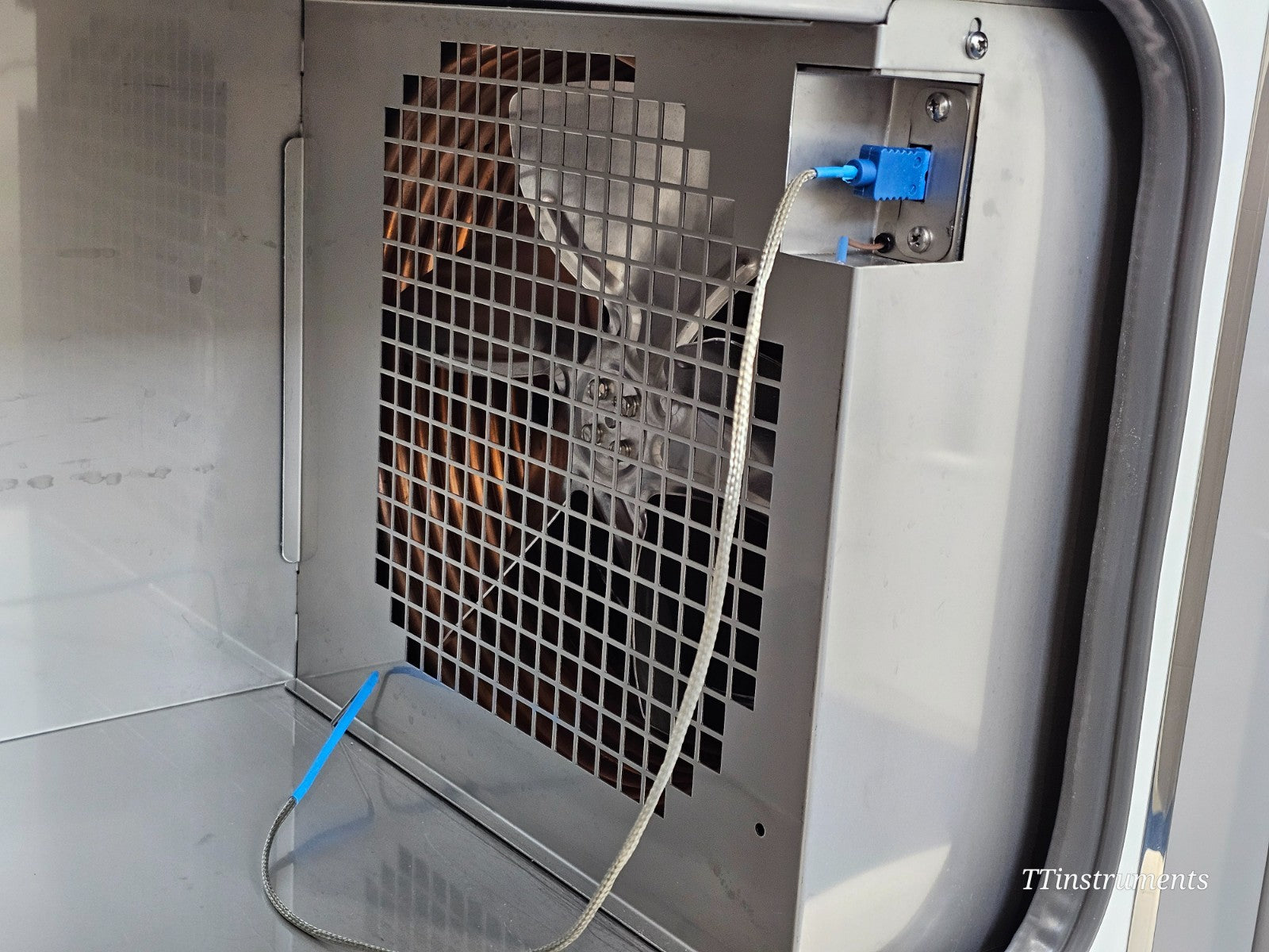CryoMed TSCM34PV interior rear wall showing copper LN2 coil, circulation fan behind stainless steel guard and Type T thermocouple connector