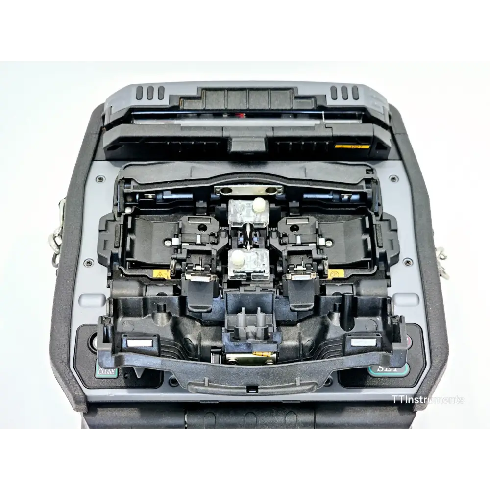 Fujikura 90S+ fusion splicer angled side view showing USB port, battery pack BTR-15 and carry handle