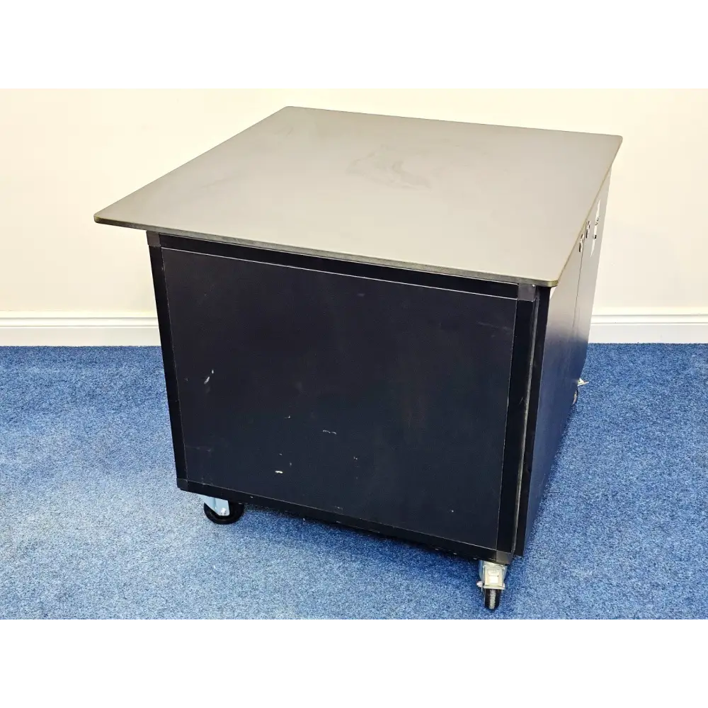ionBench BCH120NE78 mass spec bench side view showing black cabinet body, grey worktop overhang, and castors