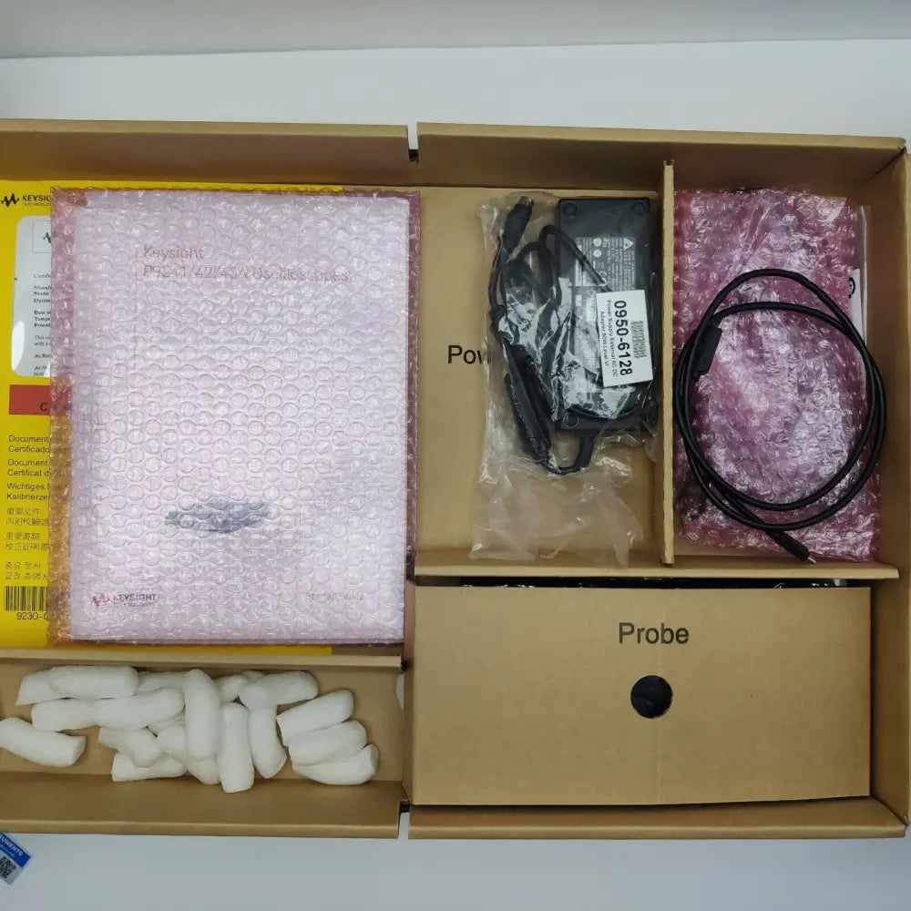 Keysight P9241A accessories box interior showing documentation, power adapter (0950-6128), power cord, and probe sub-box